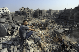A man sits on the rubble as others wander among debris of buildings that were targeted by Israeli airstrikes in Jabaliya refugee camp, northern Gaza Strip, Wednesday, Nov. 1, 2023. – AP